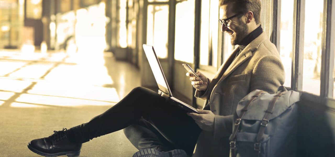 Mann mit Smartphone und Laptop-Rucksack