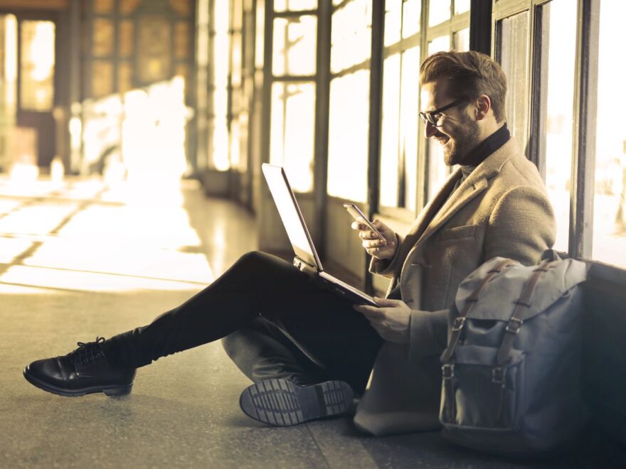 Mann mit Smartphone und Laptop-Rucksack